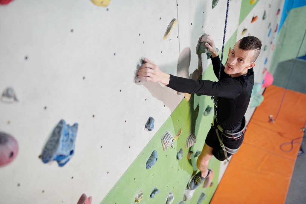 man trying indoor rock climbing